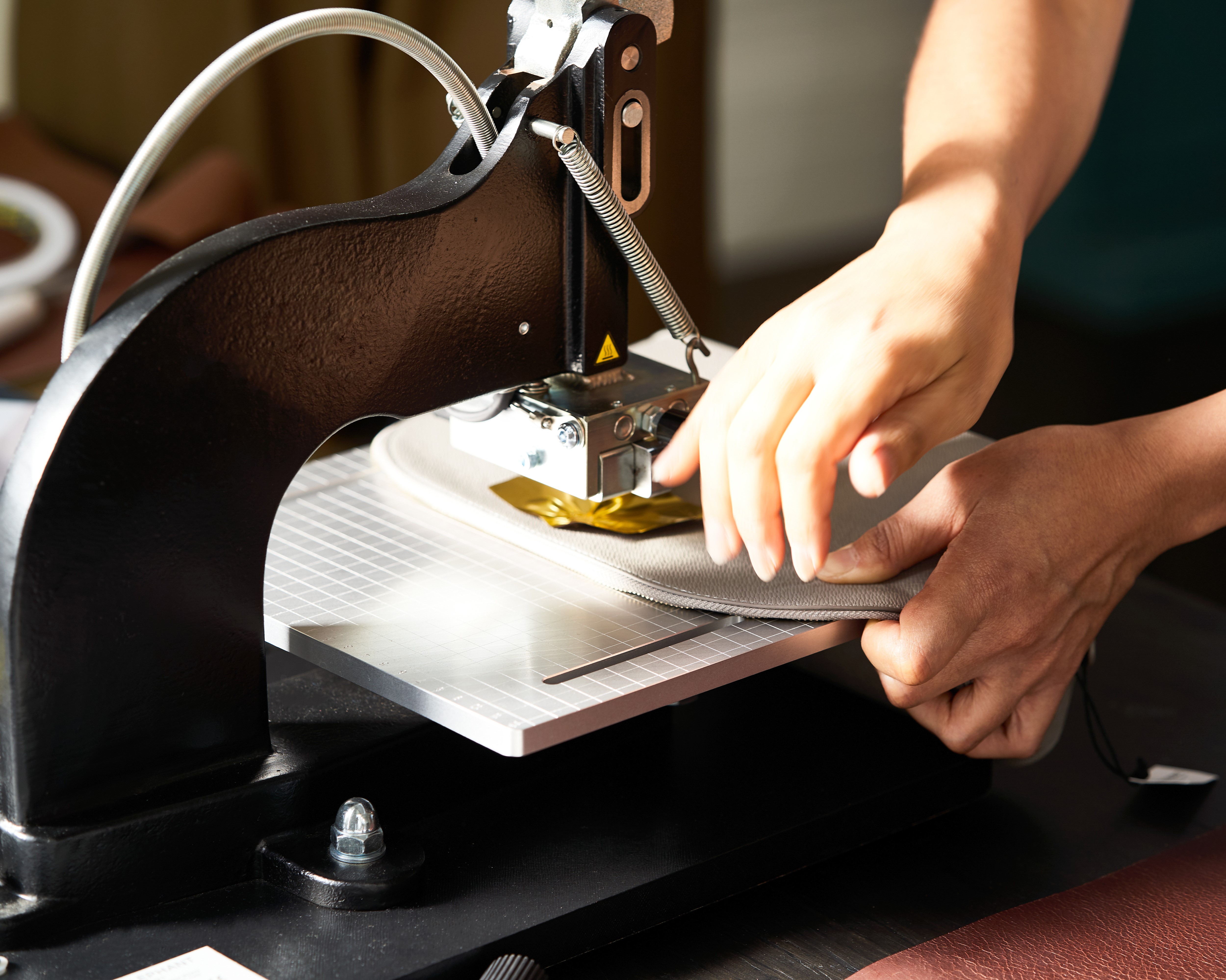 A person sewing a piece of fabric with a small sewing machine.