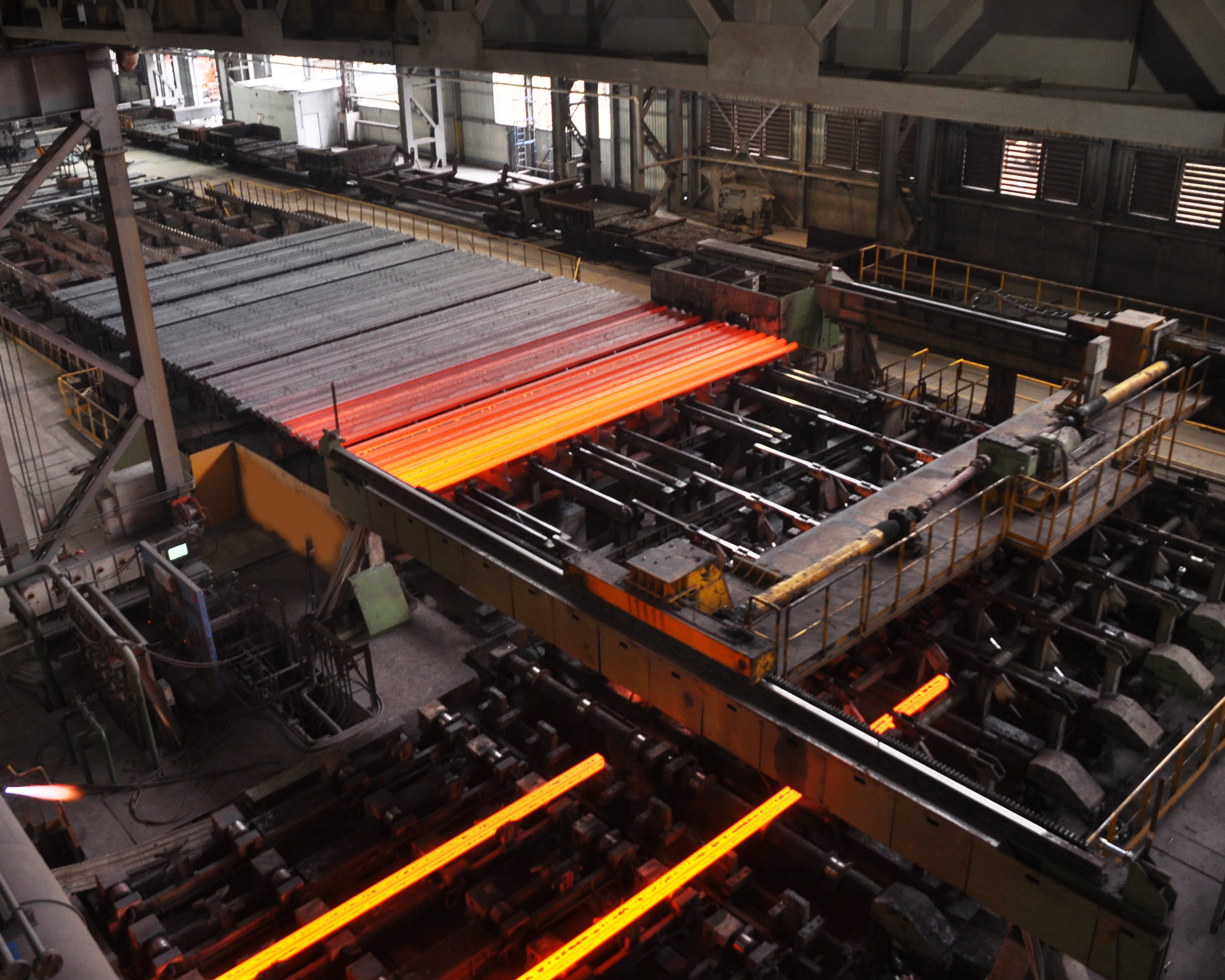 Machinery moving steel rods through a large process on site.