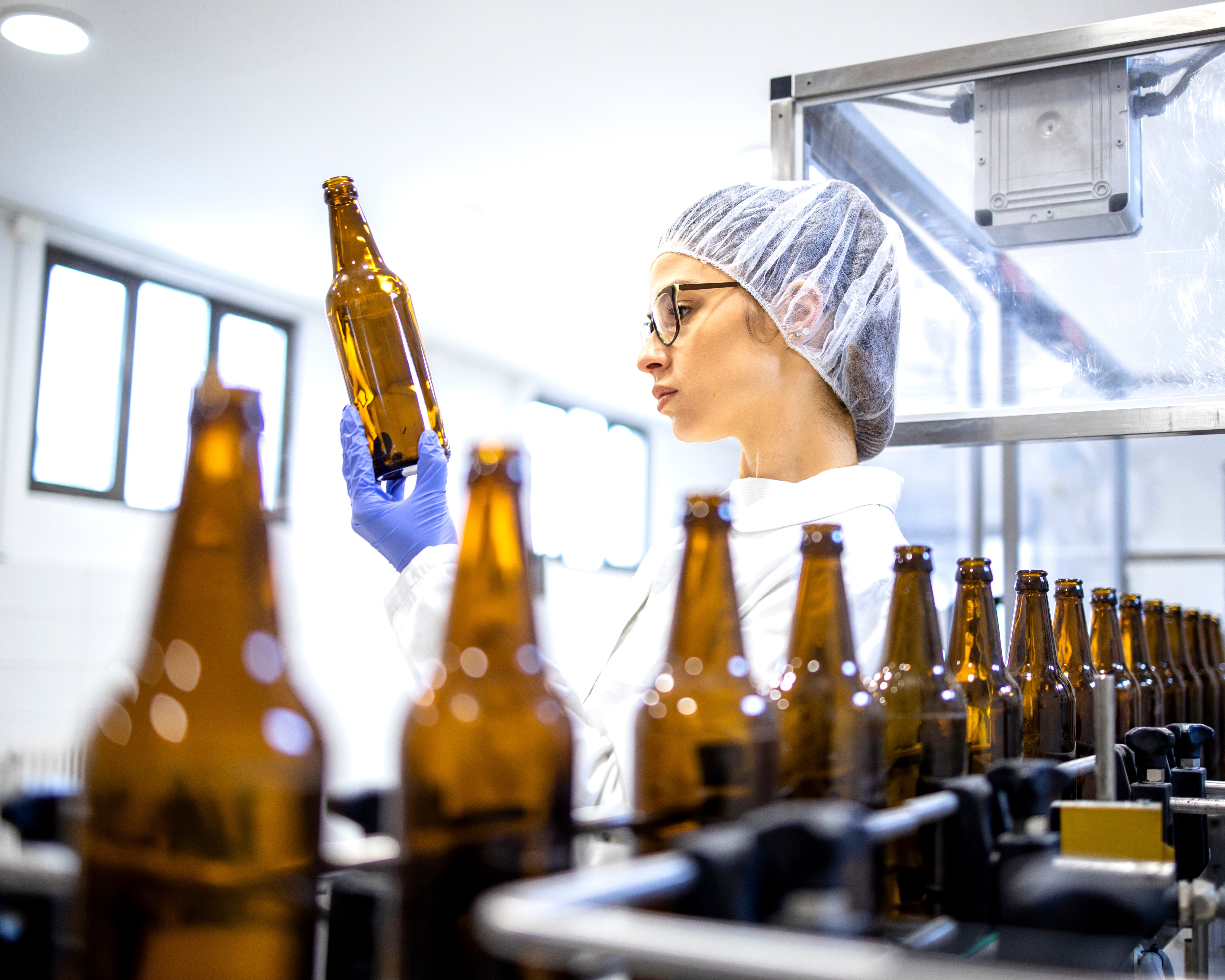 Woman inspecting a bottle picked out from a bottling line.