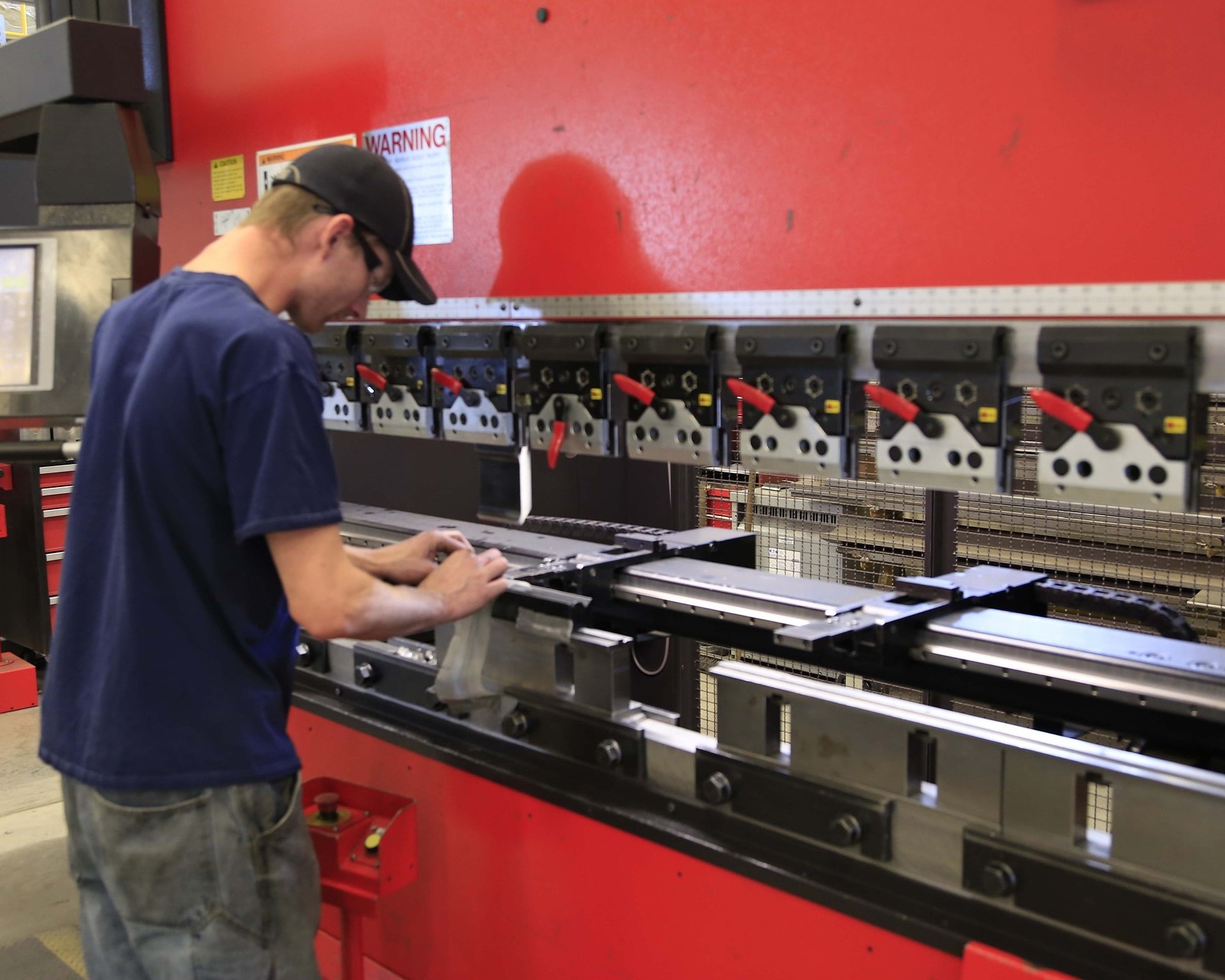 A man is engaged in operating machinery within a factory setting, highlighting the work environment.