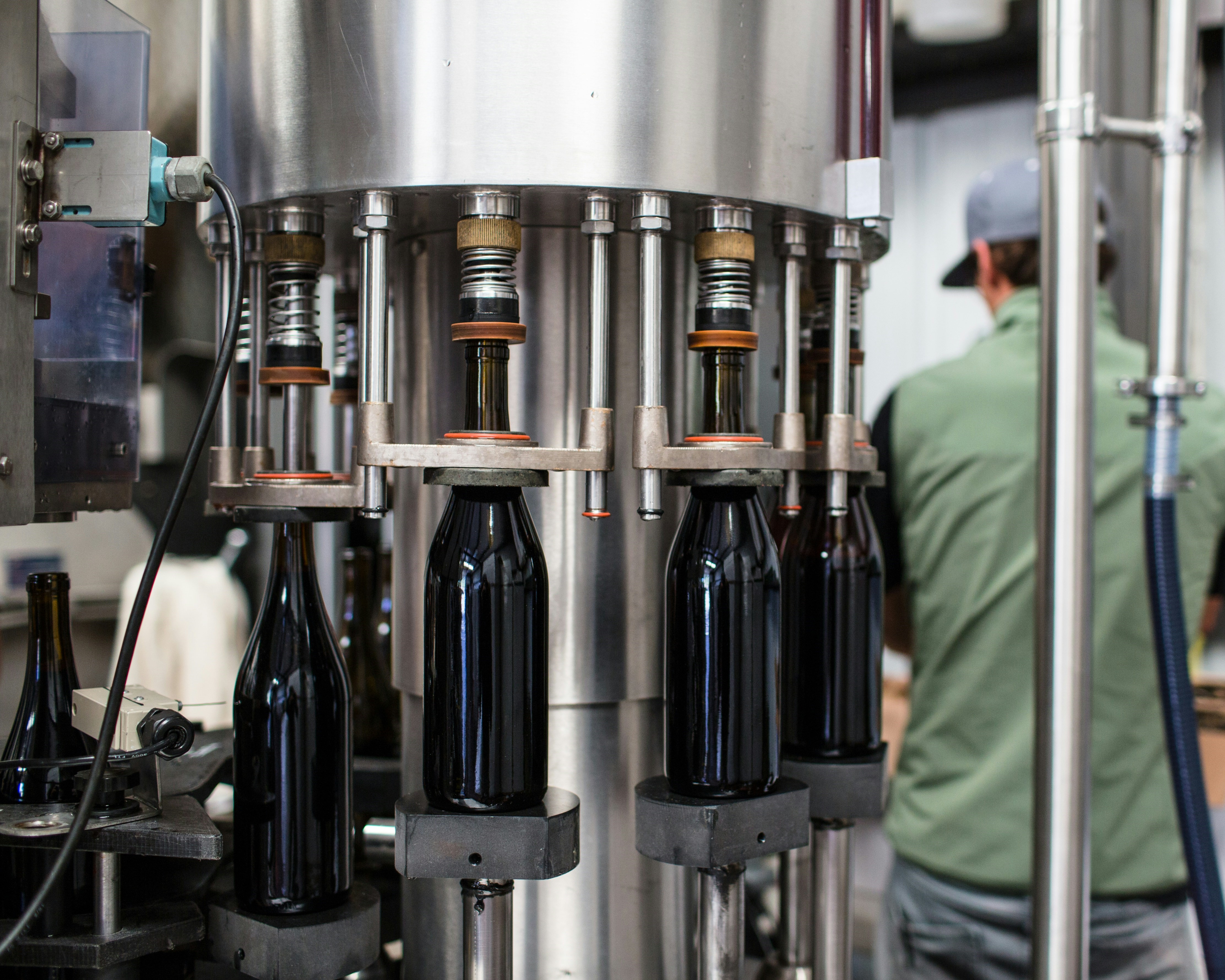 A man works diligently on a machine that produces wine, highlighting the craftsmanship involved in winemaking.