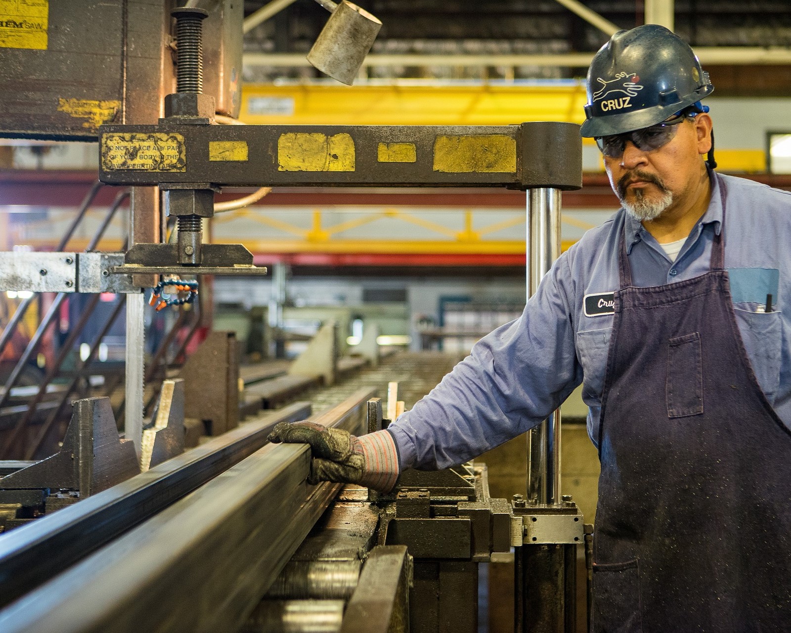 A man inspecting a piece of machinery used to cut metal.